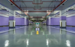 A large warehouse or factory floor with smooth, glossy epoxy flooring marked with safety lines.
